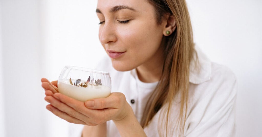 10 Best Candle Scents of 2026: Top Picks Loved by Real Buyers 23 lady smelling candle in a glass bottle