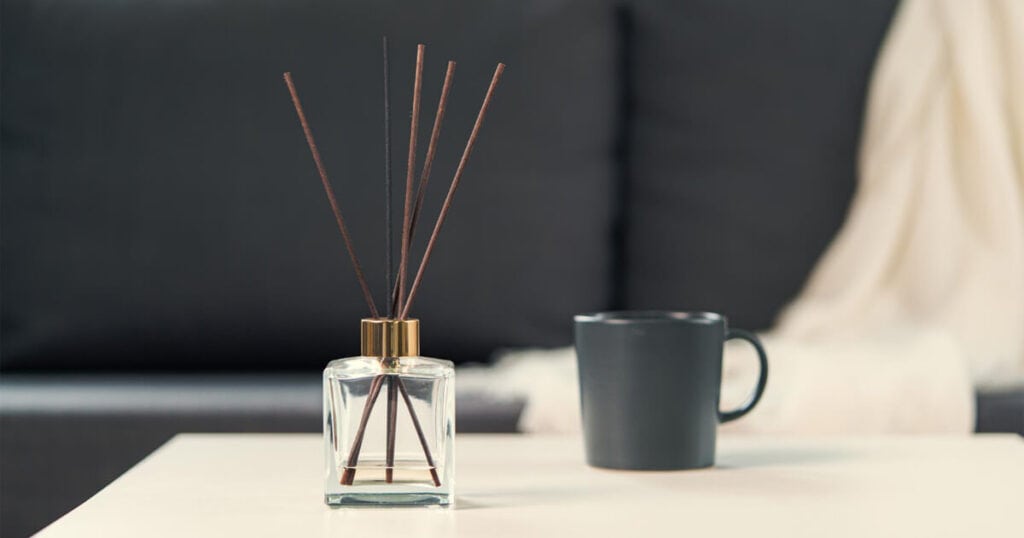 clear reed diffuser bottle in a white table with black mug