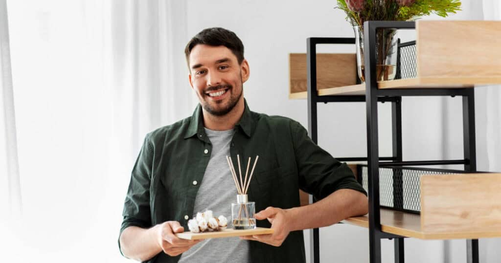 man holding a tray with reed diffuser and flower petals